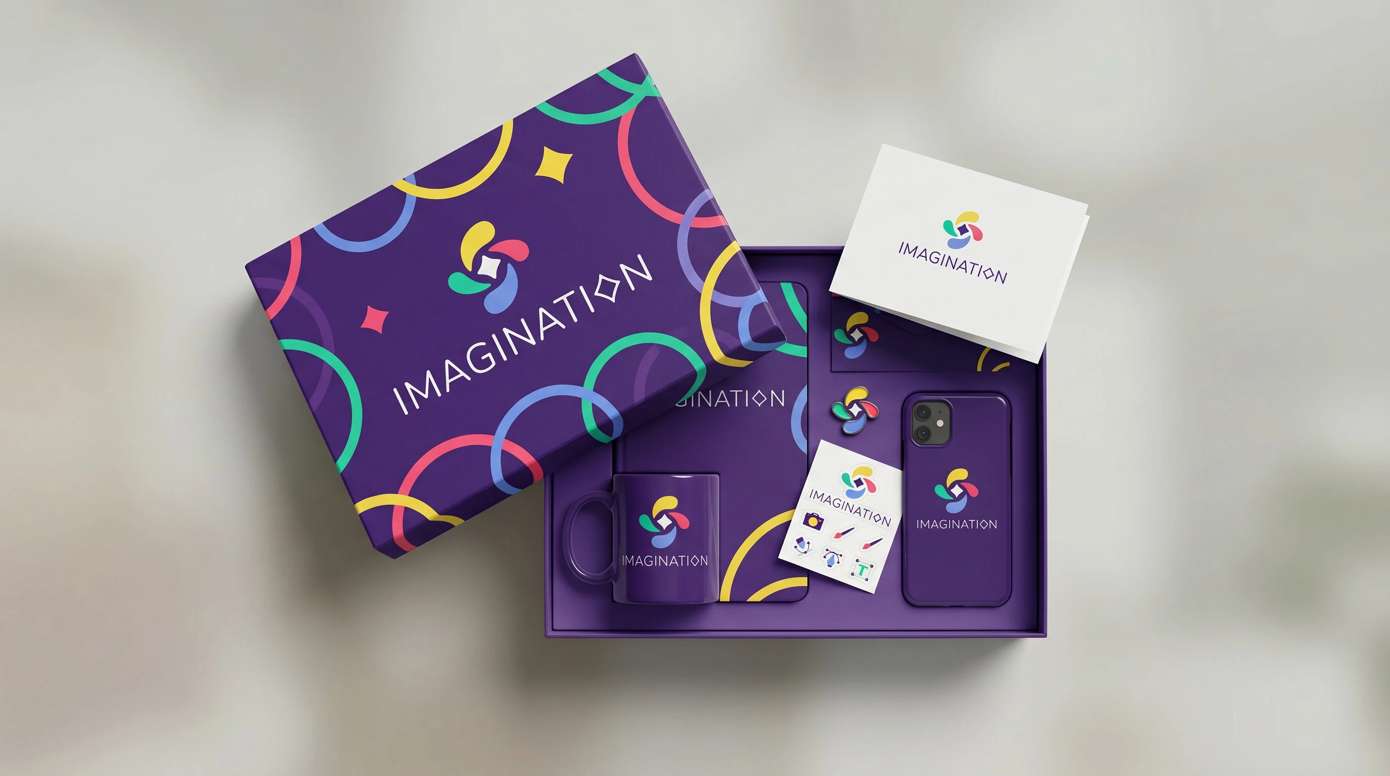 Подарочный набор для студентов IMAGINATION снят сверху на нейтральном фоне с мягким светом, в центре — прямоугольная коробка, оформленная насыщенным фирменным паттерном на глубоком фиолетовом фоне, с 